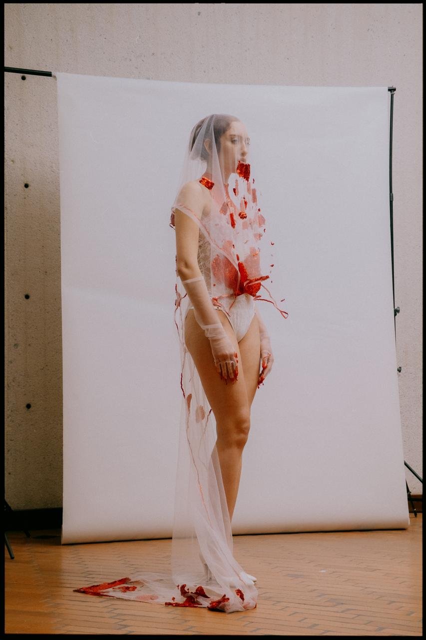 Look de Velvet Sin: body de encaje blanco con detalles rojos y velo, cuerpo completo
